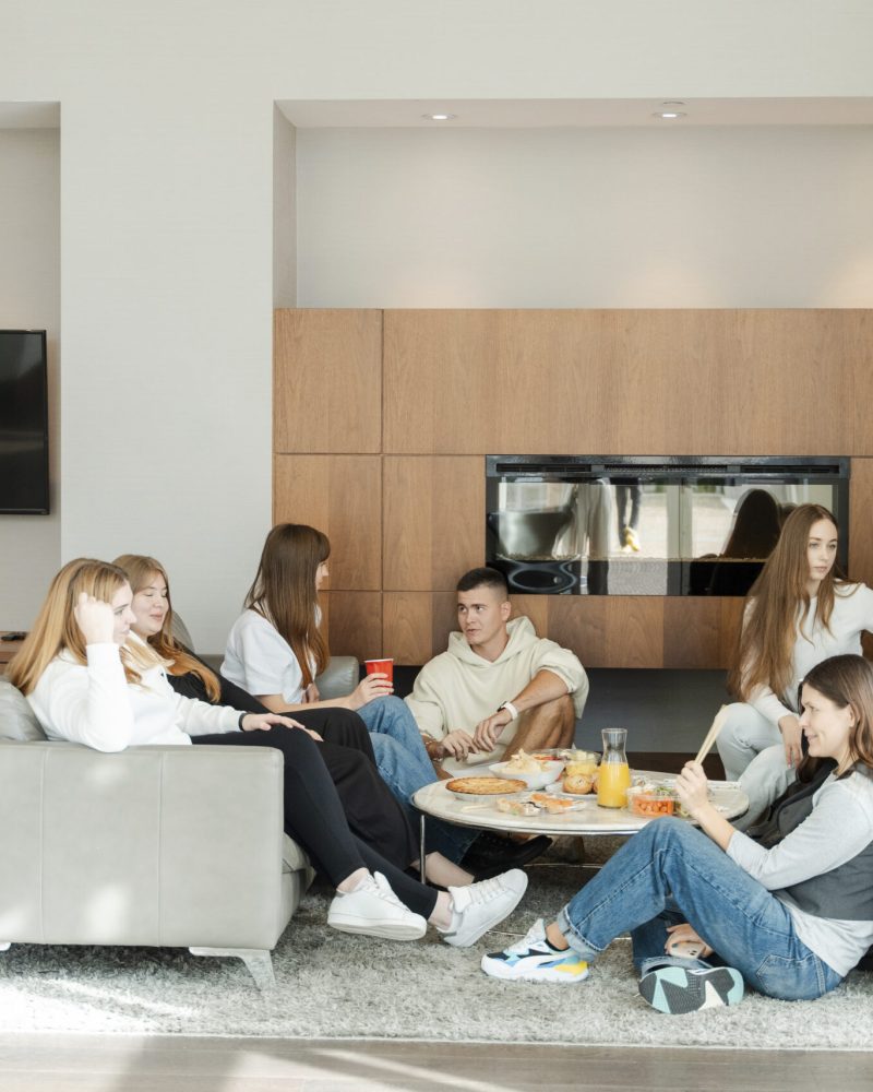 Young colleagues sitting at modern home, eating tasty food and talking with each other. Happy people lifestyle concept